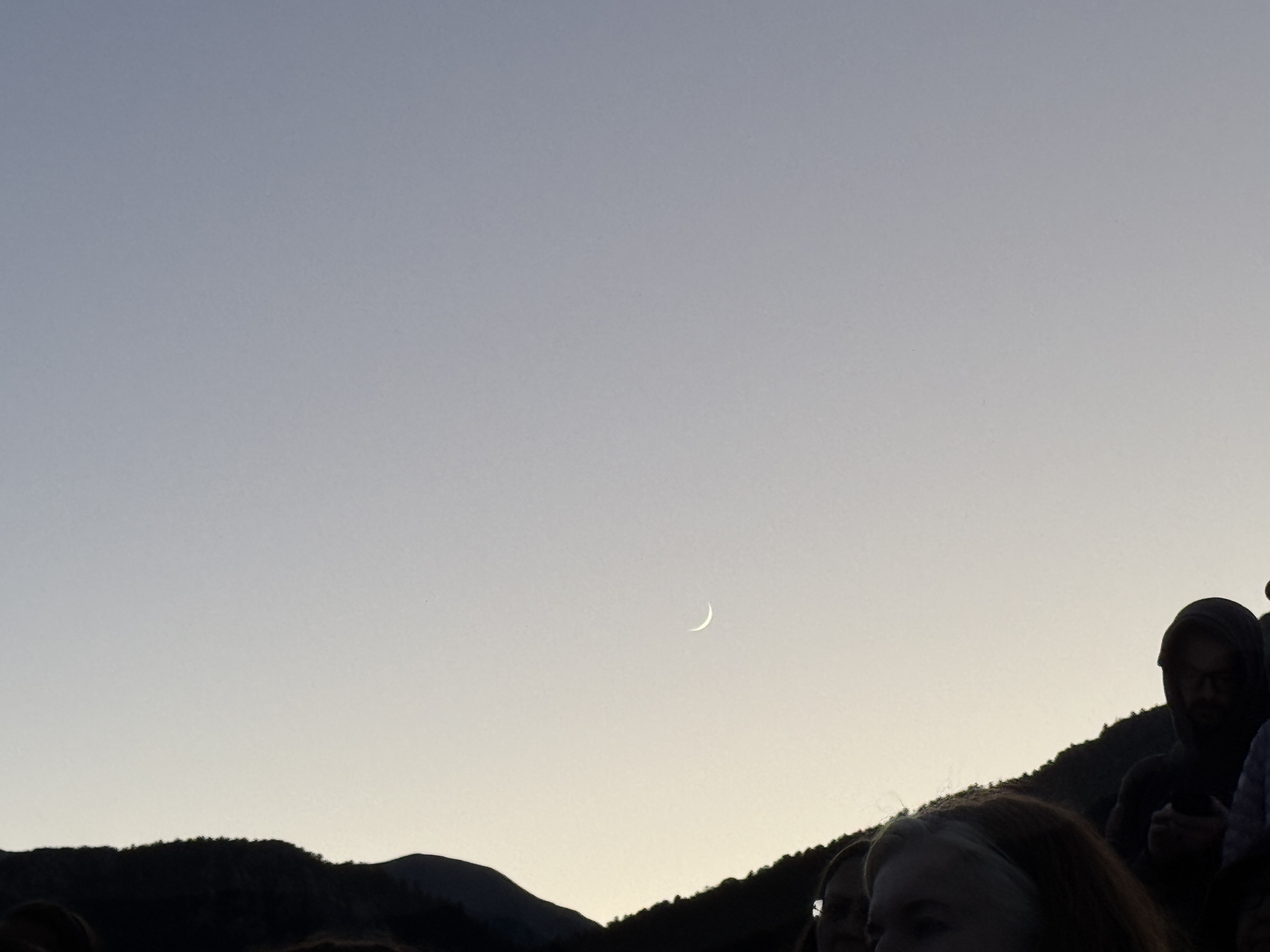 Waxing crescent moon setting behind the mountains